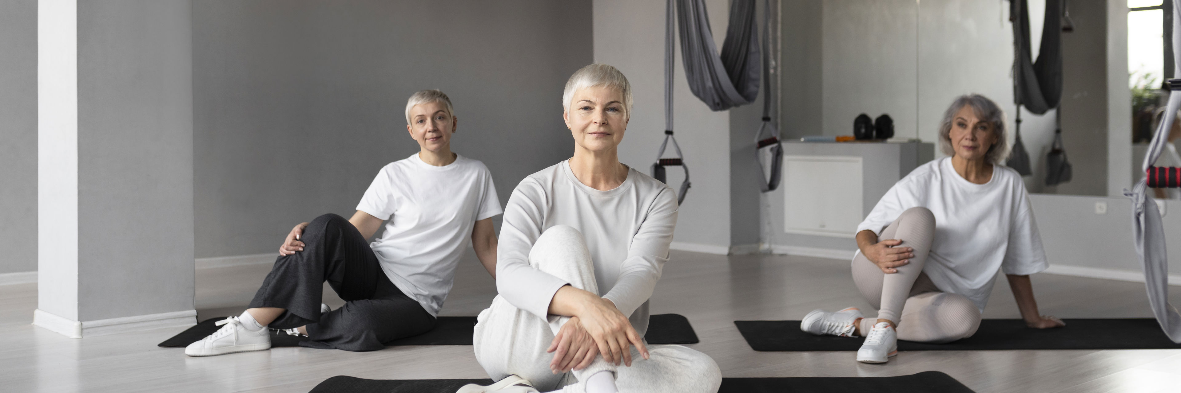 Tre kvinder sidder på yogamåtter på gulvet