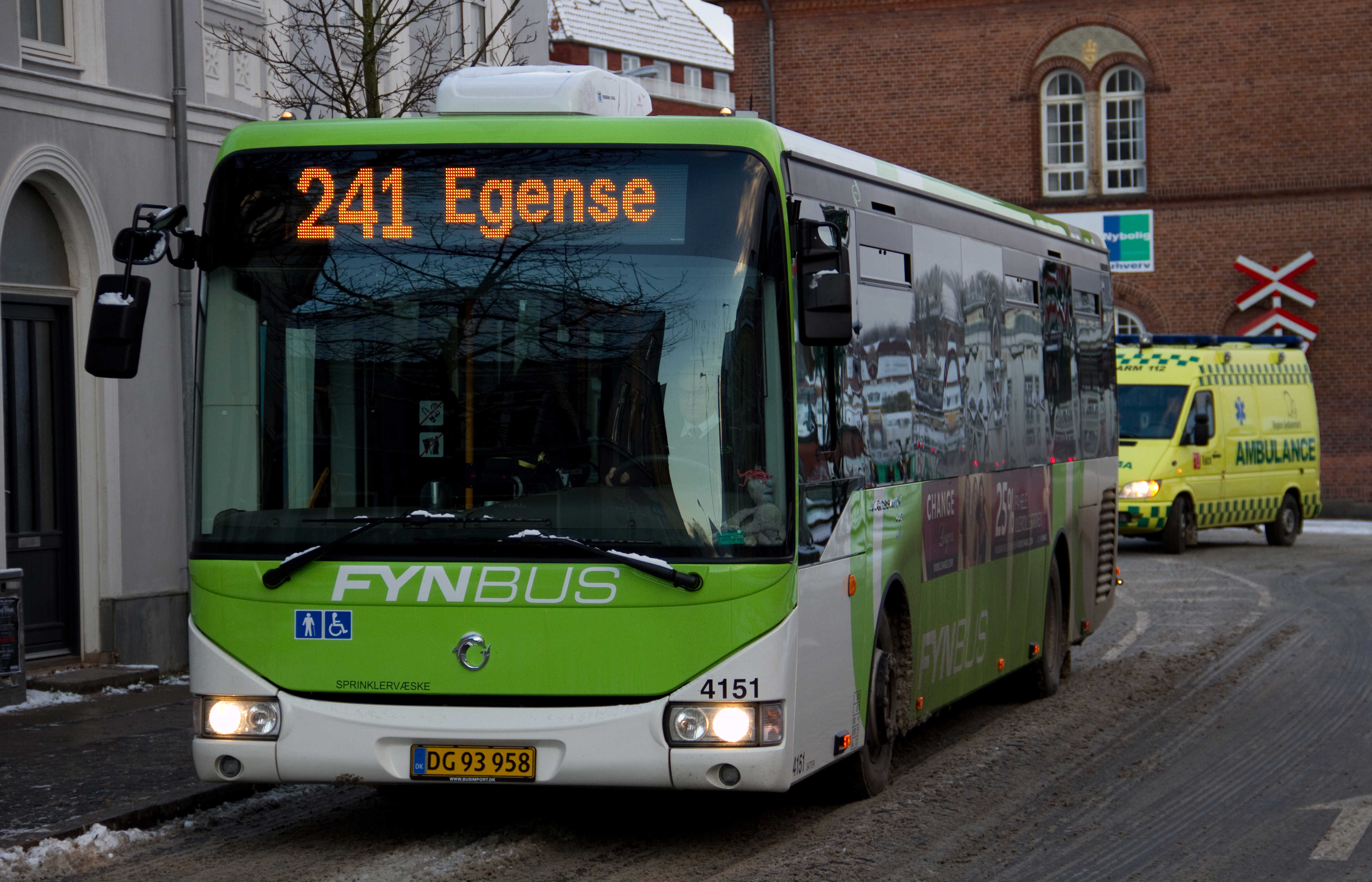 En grøn og hvis bus med 'Egense' som destination kører på en vej i byen.