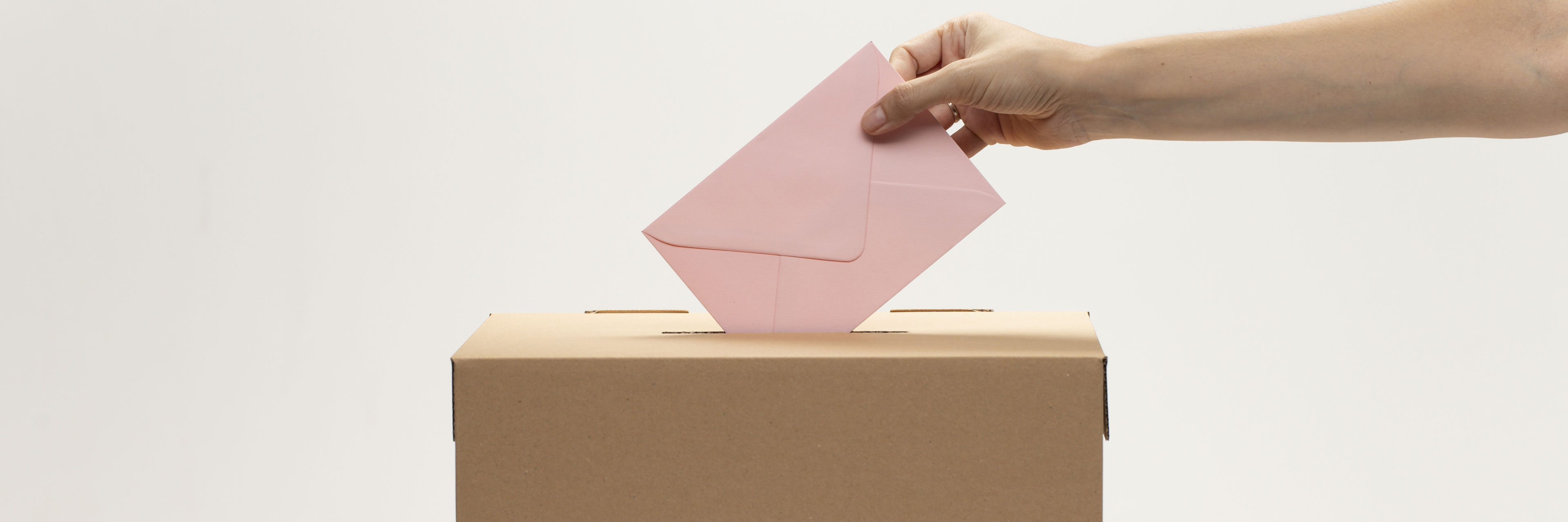 En kvindelig hånd putter en konvolut i en stemmekasse