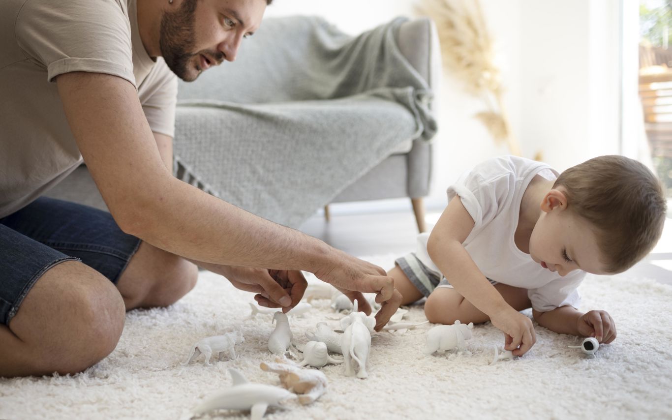 Far og barn leger med små legetøjsdyr