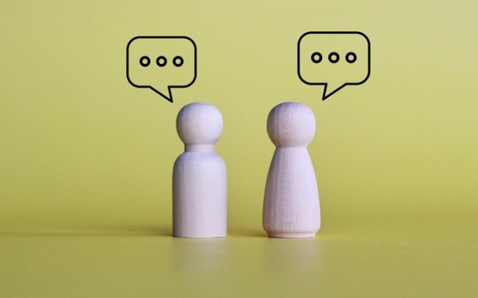 To træ brikker - en mand og en kvinde - har talebobler over deres hoveder