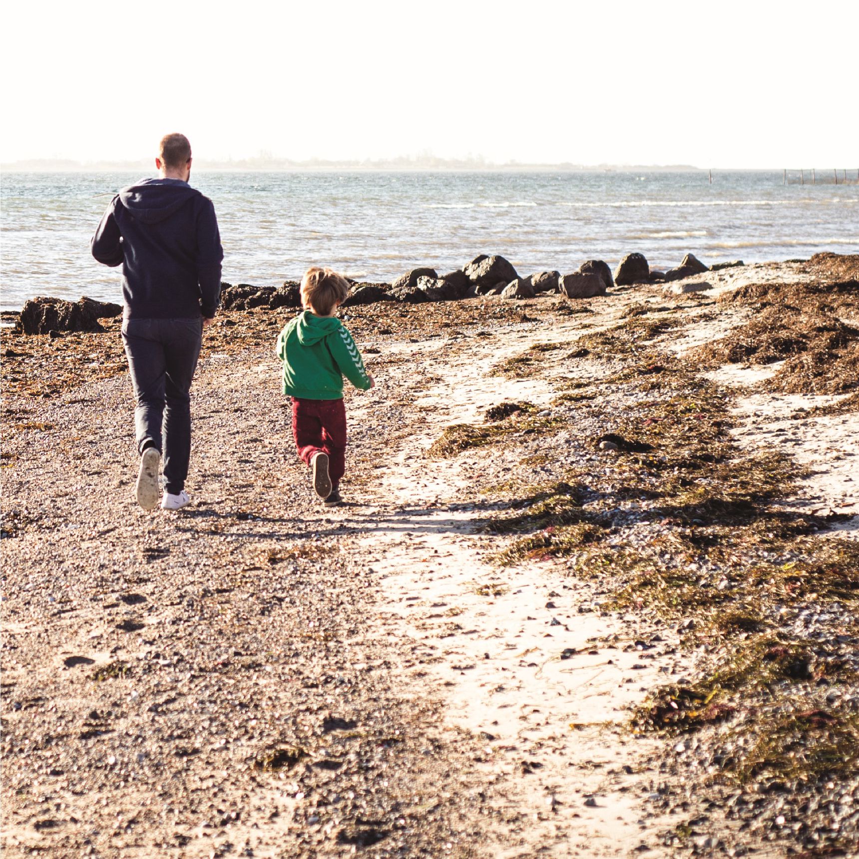 Far og barn løber på stranden