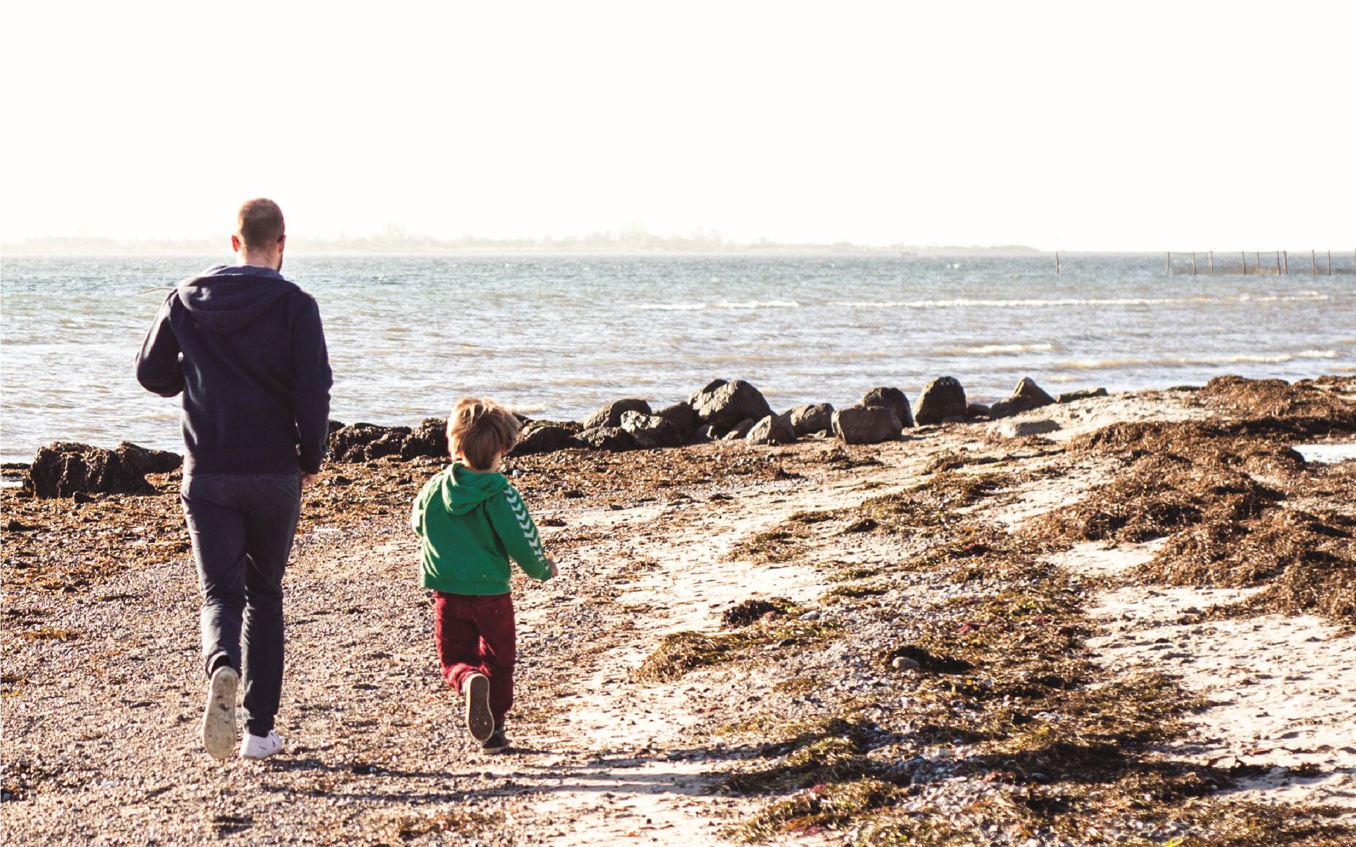 Far og barn løber på stranden