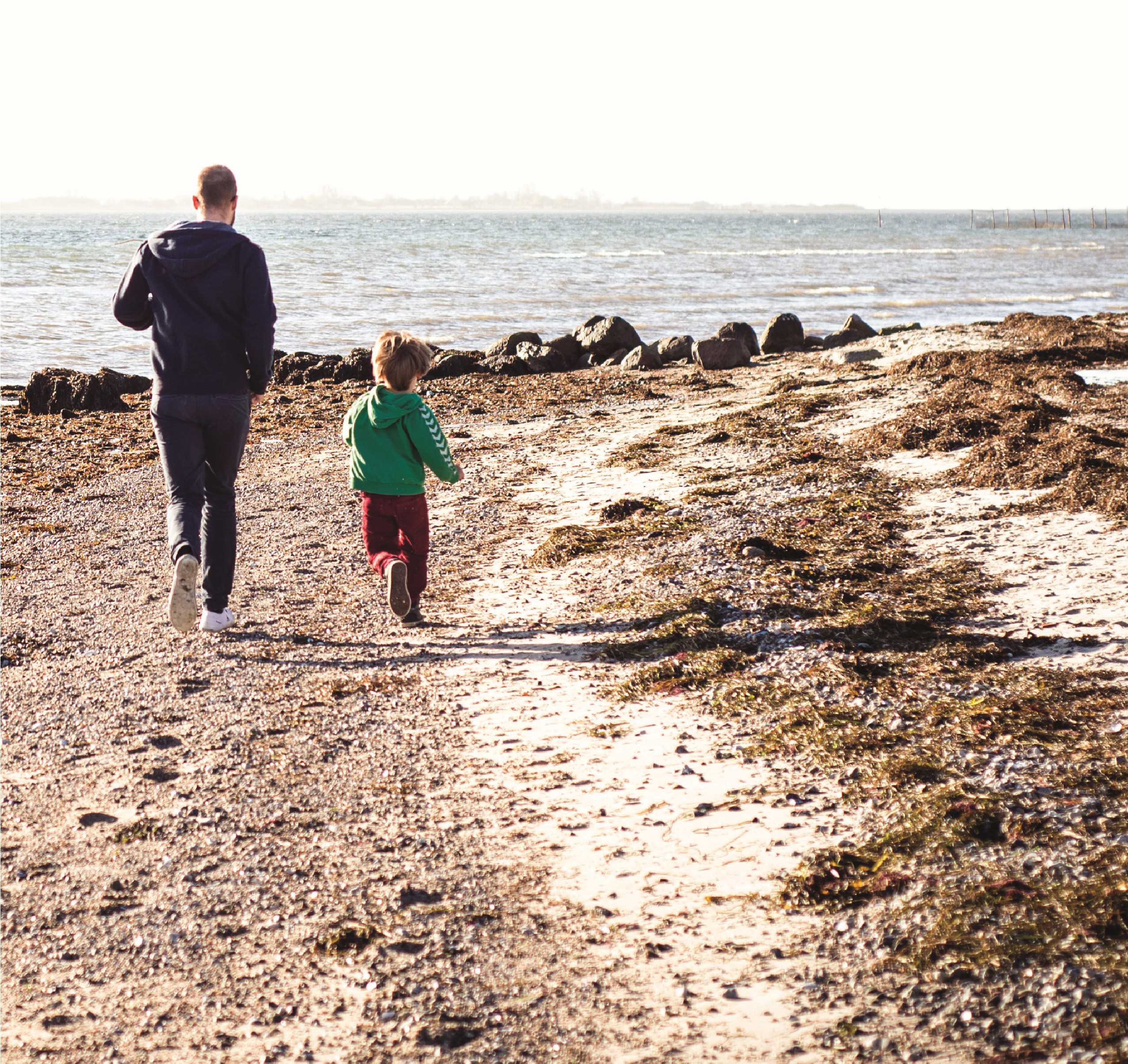 Far og barn løber på stranden