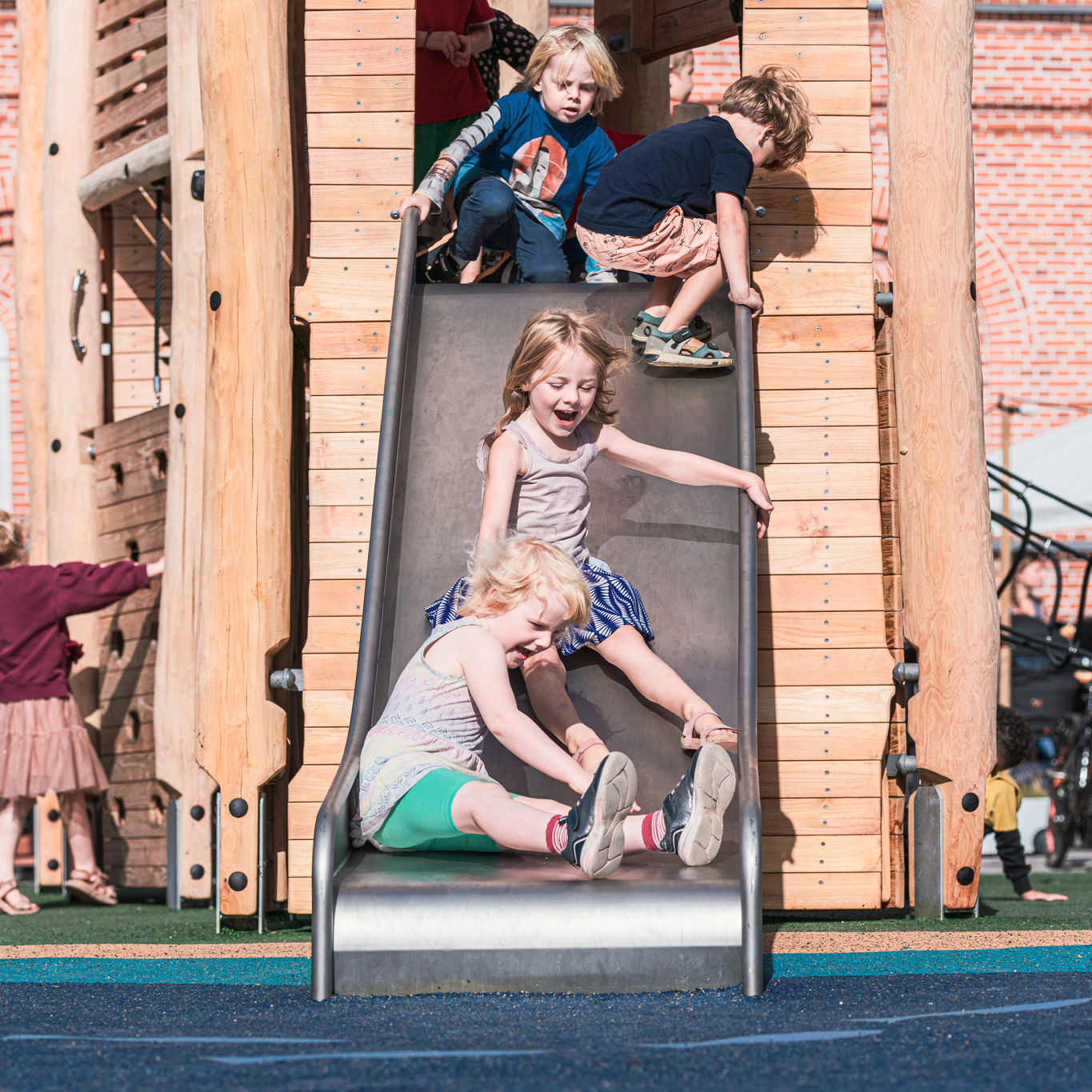 Børn rutcher ned af en rutchebane på en legeplads