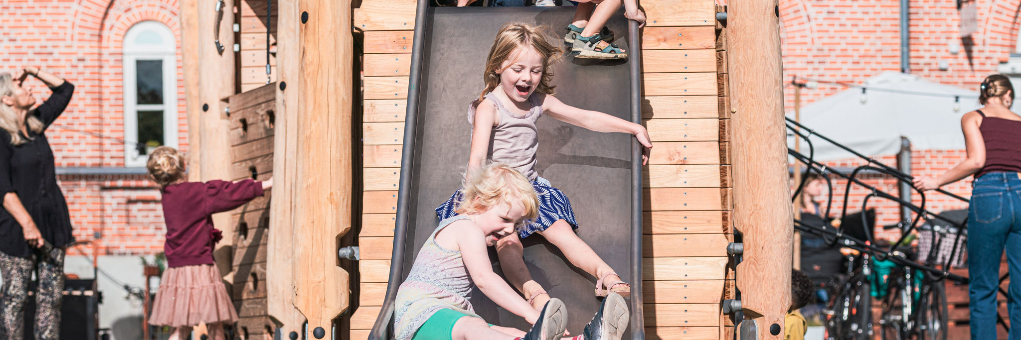 Børn rutcher ned af en rutchebane på en legeplads