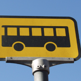 Et gult skilt med et ikon af en sort bus.