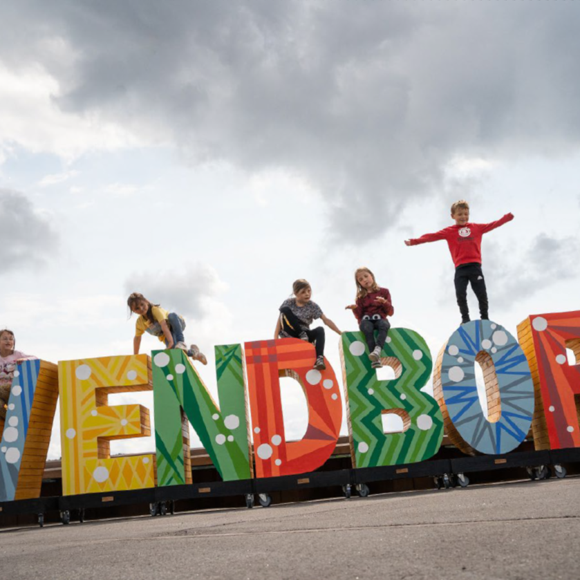 Børn fra indskolingen leger på store farverige bogstaver, hvor der står Svendborg