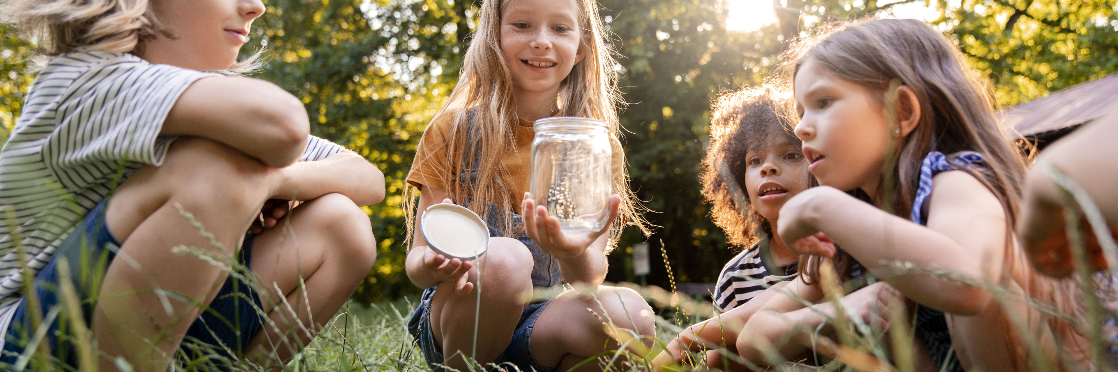 Fire børn kigger på glas med sommerfugl