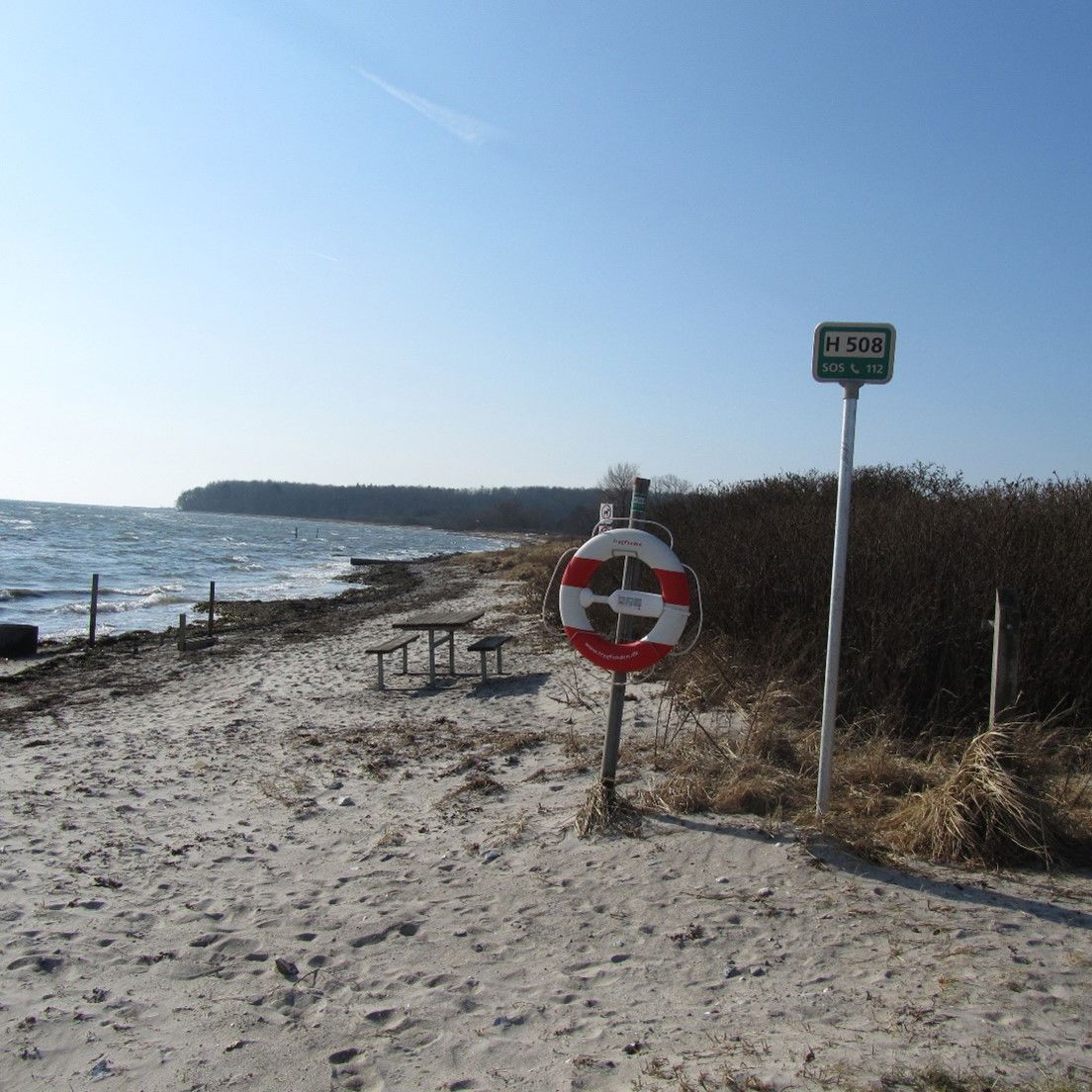 Stranden ligger naturskønt ved et offentligt grønt område med plads til ophold og med udsigt til Langeland.
