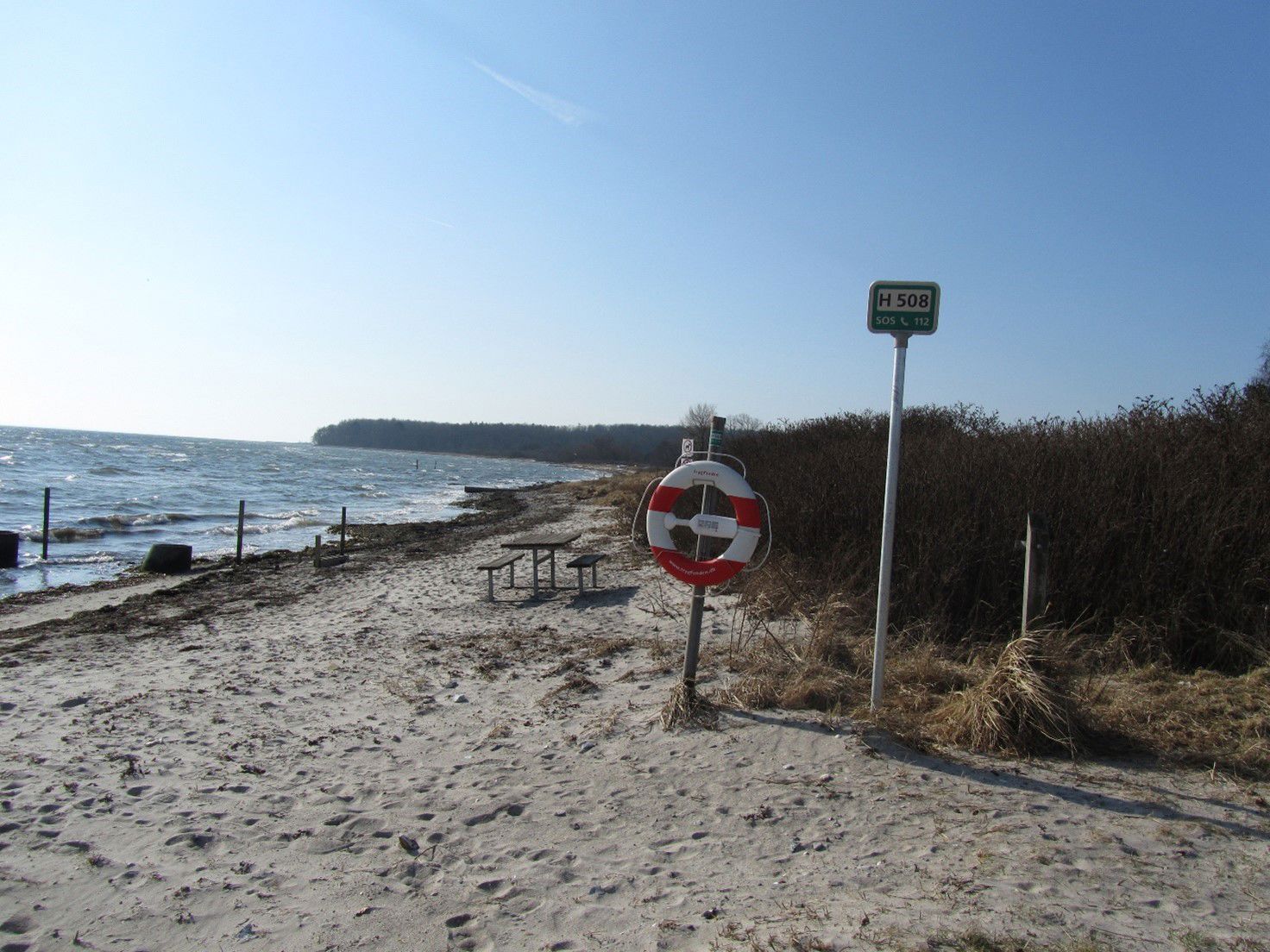 Stranden ligger naturskønt ved et offentligt grønt område med plads til ophold og med udsigt til Langeland.