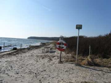 Stranden ligger naturskønt ved et offentligt grønt område med plads til ophold og med udsigt til Langeland.