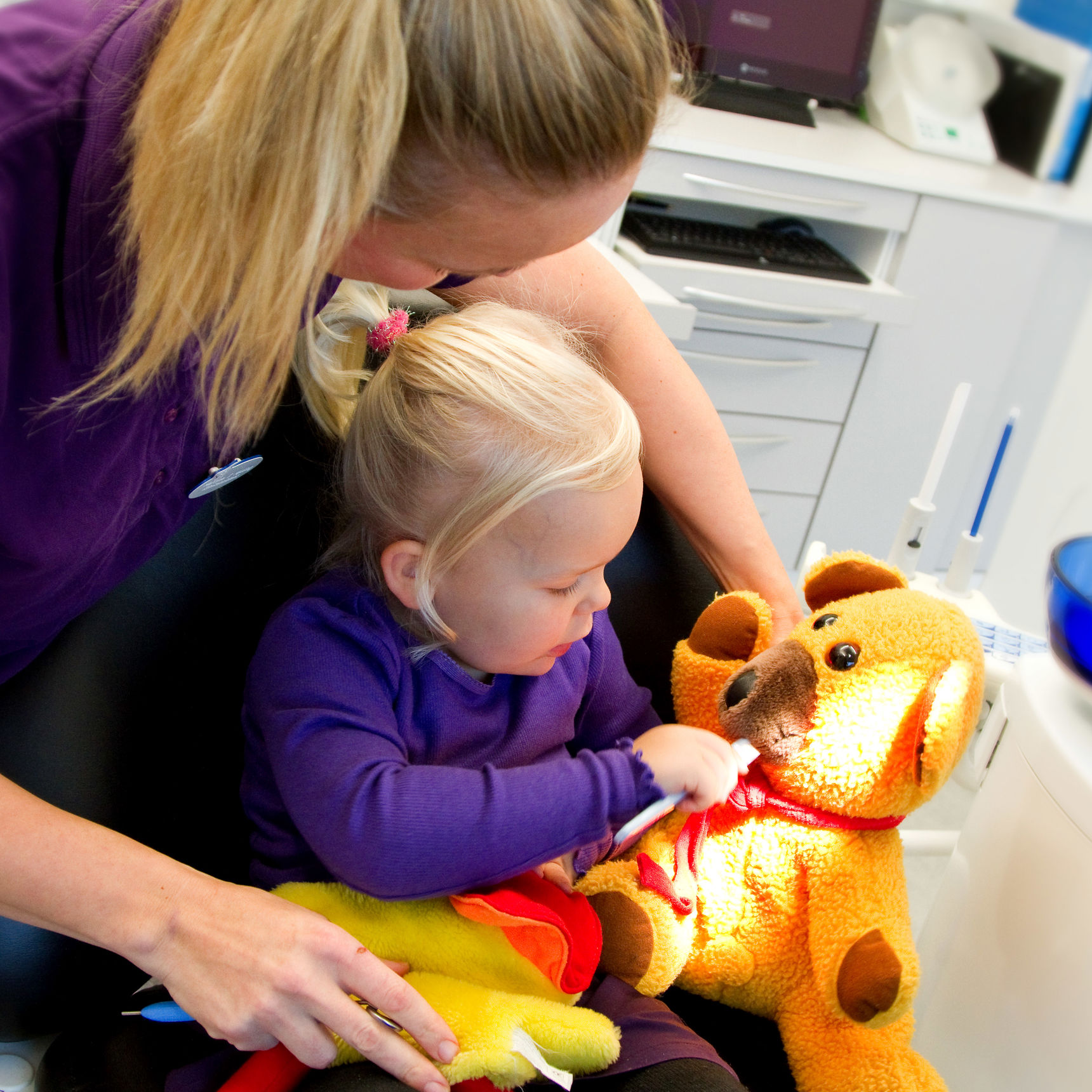 Barn ved tandlægen, børster tænder på bamse.