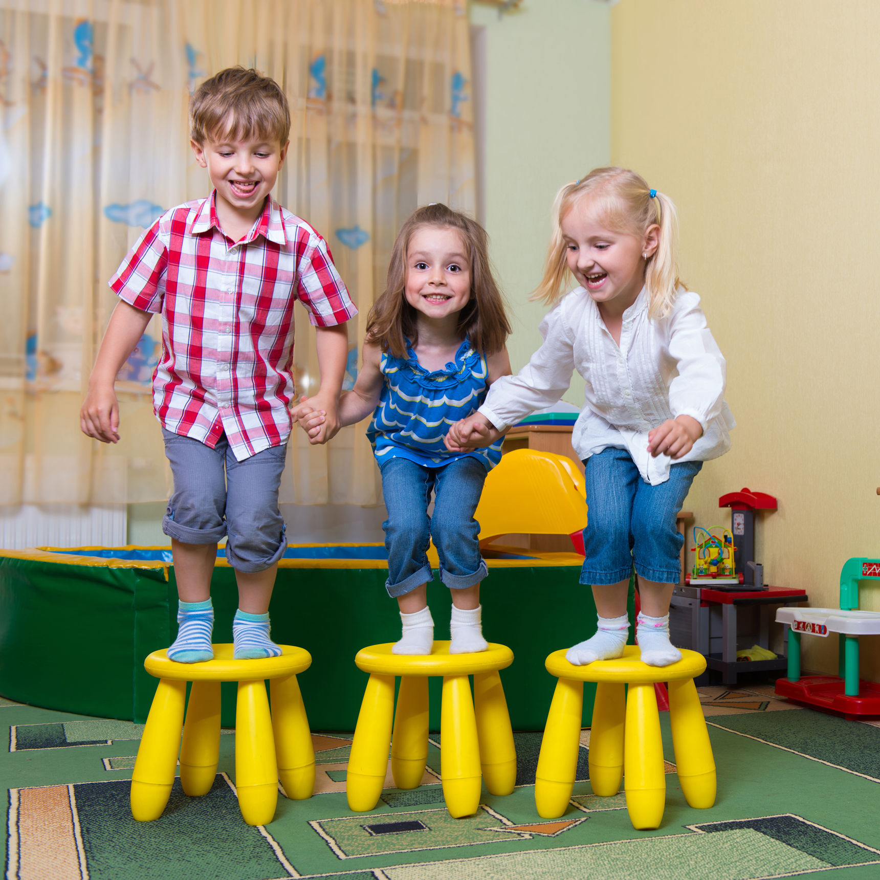 Tre børnehavebørn hopper fra hver deres skammel