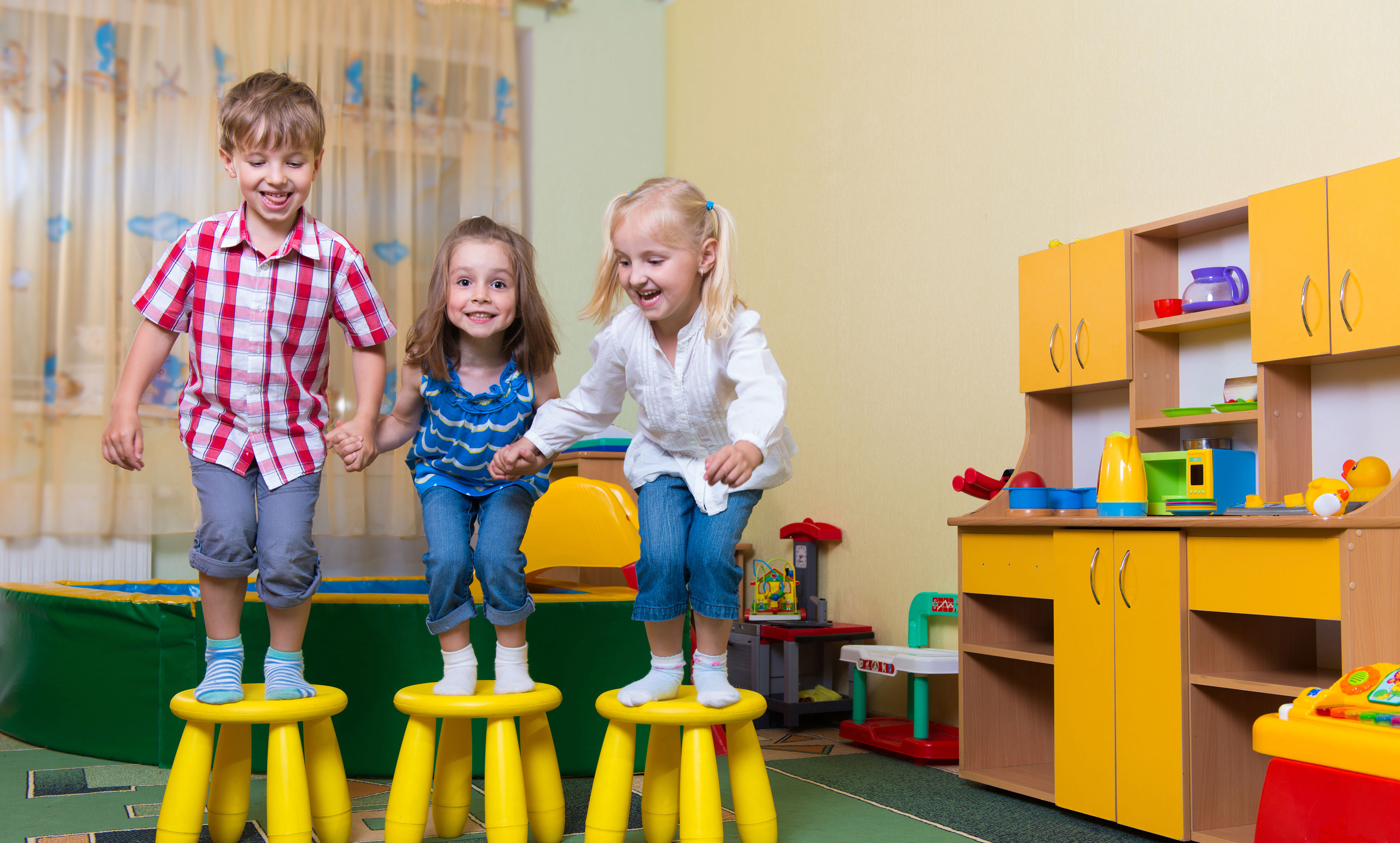 Tre børnehavebørn hopper fra hver deres skammel