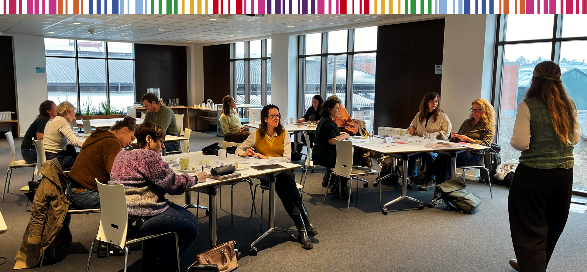 Kvinder og mænd ved borde i et mødelokale
