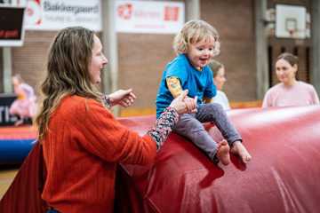 Gymnastik i SG-Huset - en voksen hjælper sit barn i spring fra høj madras