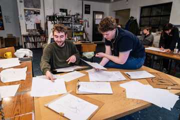 2 unge kunstnere deler tegninger ved et bord