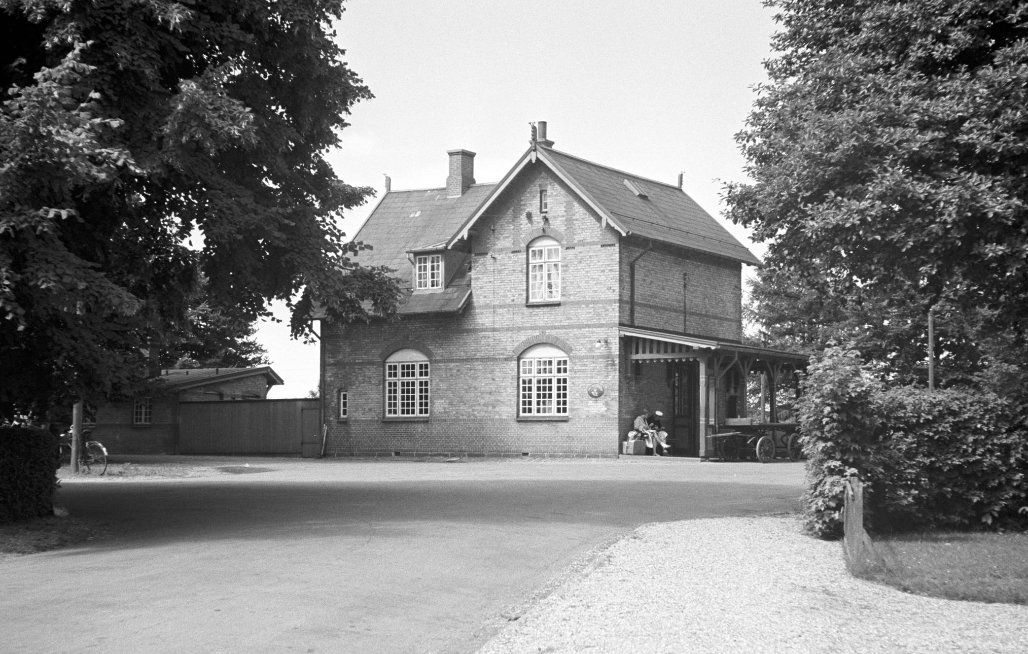 Historisk billede af Tjørnevej 9 - dengang bygningen fungerede som station. Bemærk de ventede togpassagerer under verandens tag.