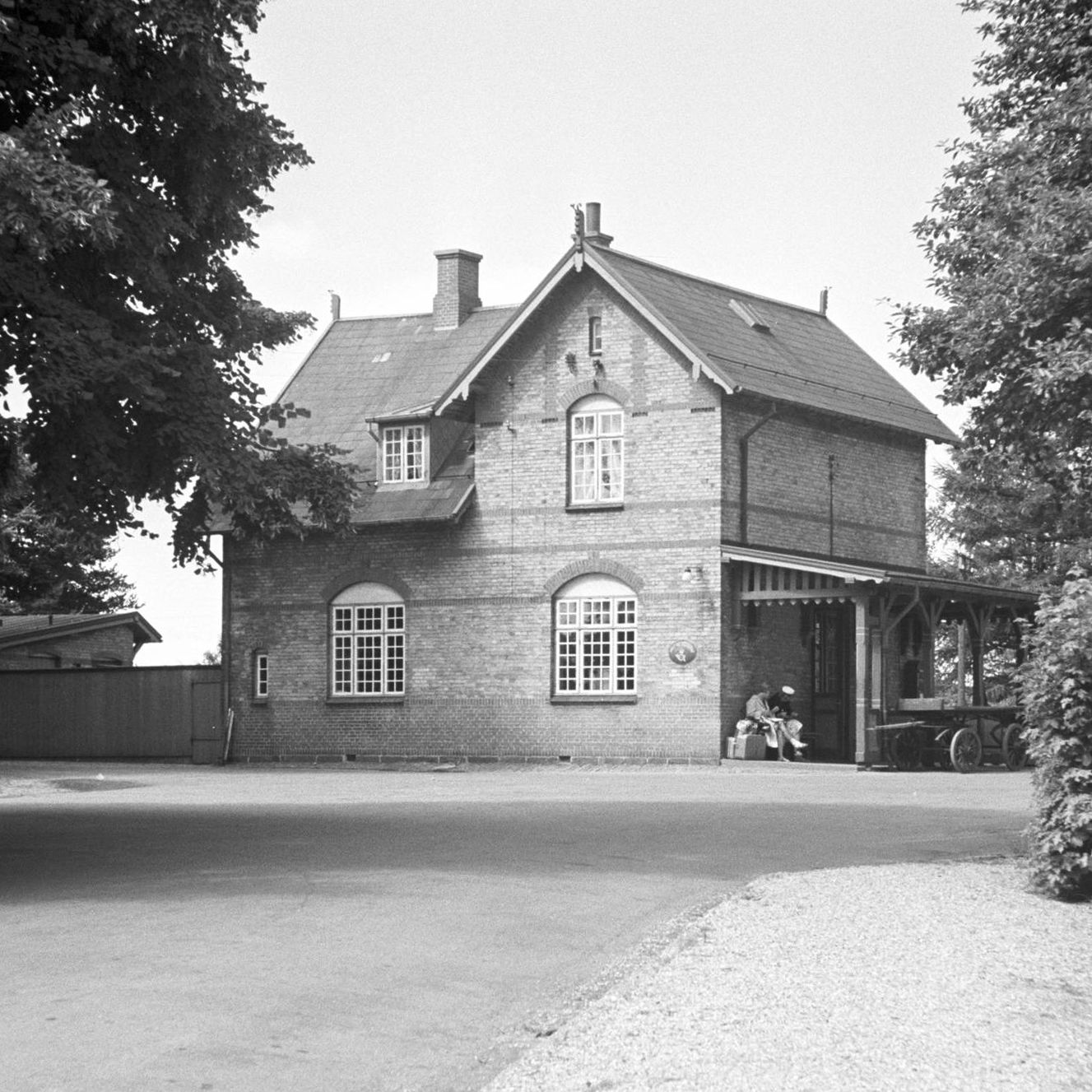 Historisk billede af Tjørnevej 9 - dengang bygningen fungerede som station. Bemærk de ventede togpassagerer under verandens tag.