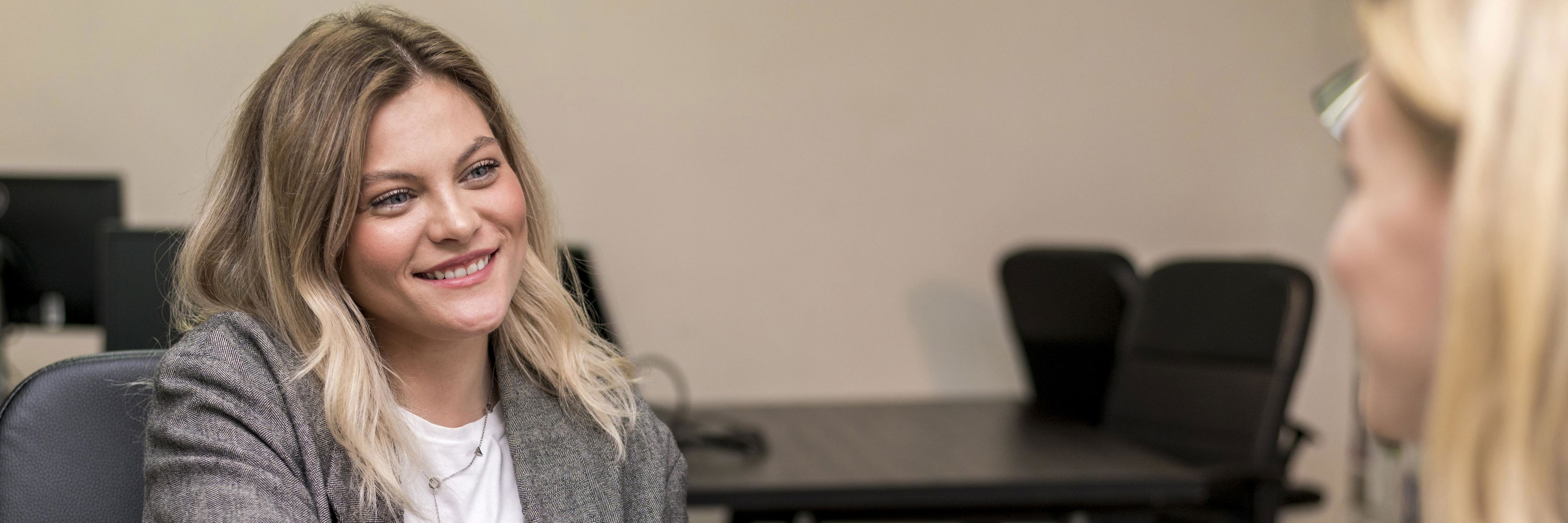 To kvinder trykker hånd. Den ene kvinde har en computer foran sig.