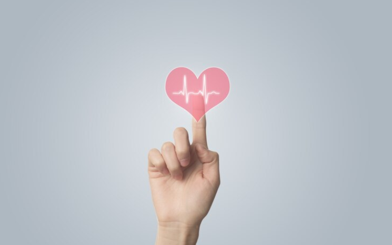 En hånd trykker på en ikon af et hjerte med hjerteslagsrytmer inden i