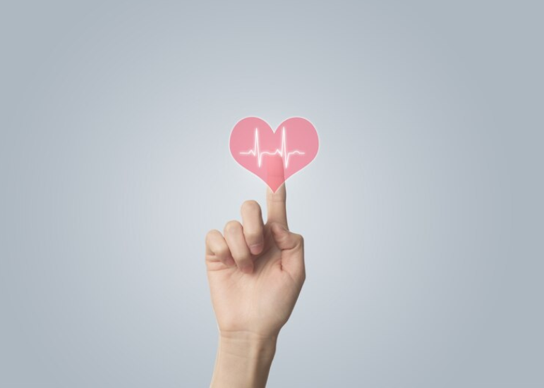 En hånd trykker på en ikon af et hjerte med hjerteslagsrytmer inden i