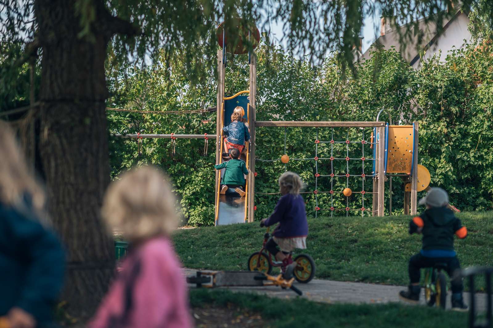 Børn på legeplads med cykler og rutsjebane