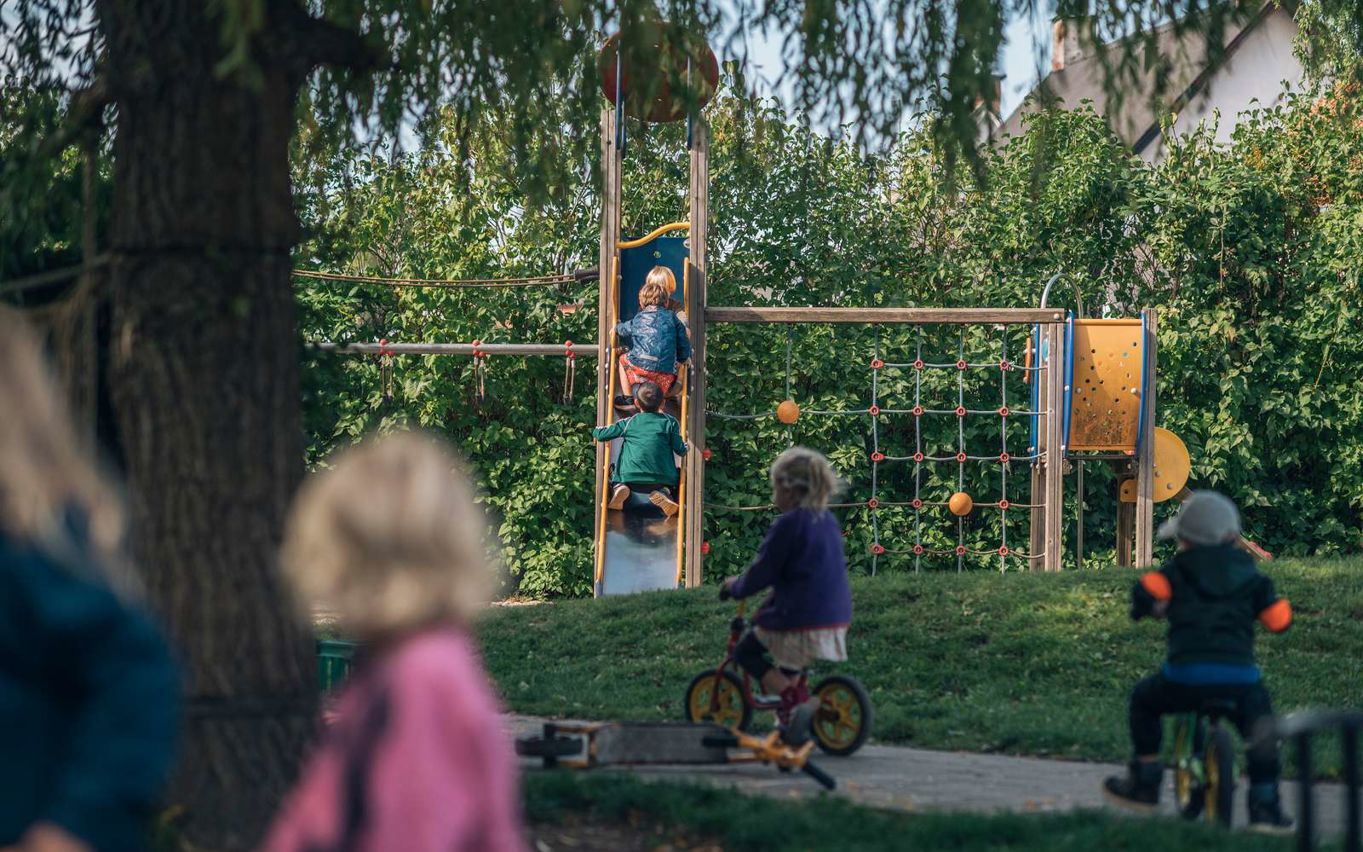 Børn på legeplads med cykler og rutsjebane
