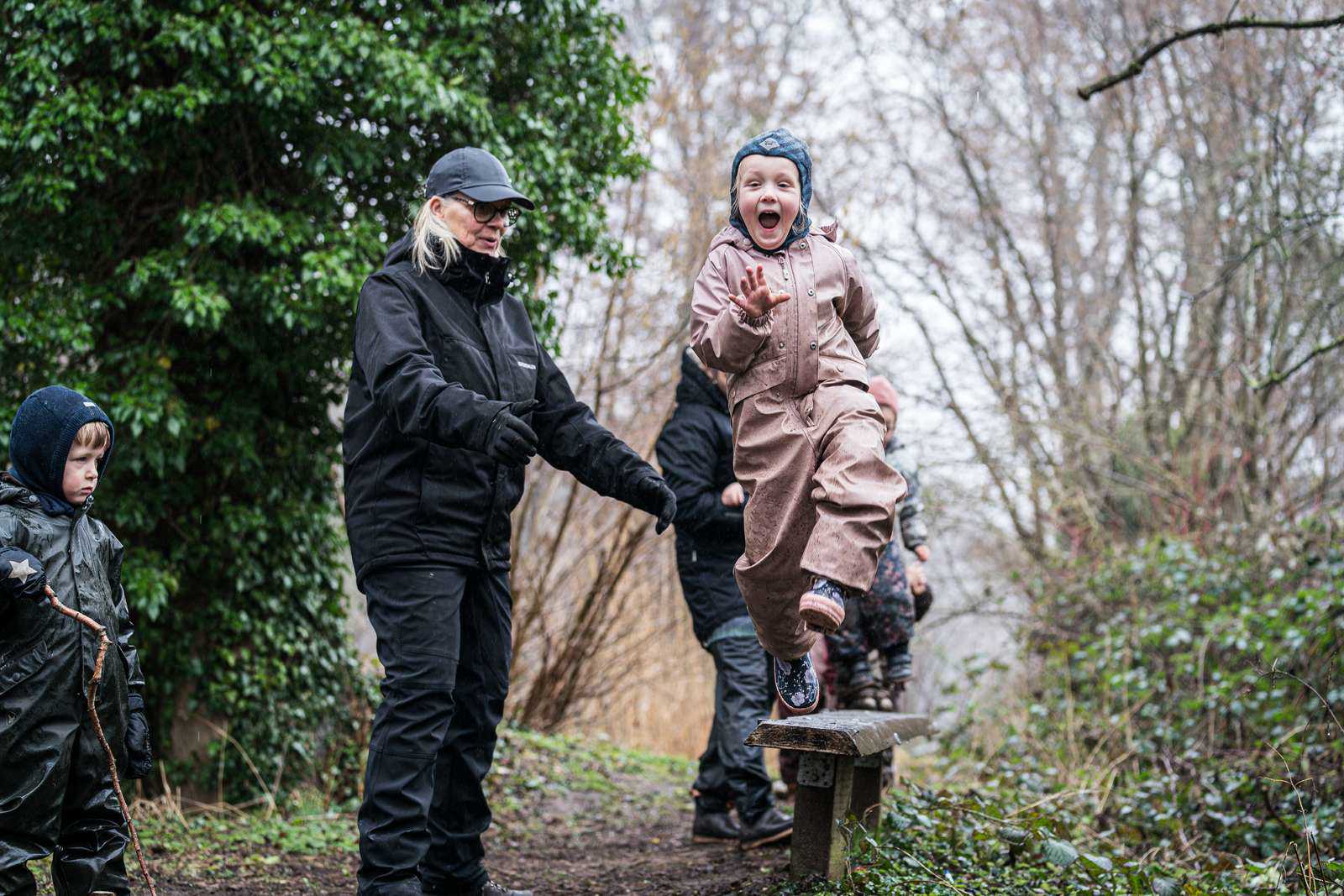 Et barn i Skårup Skovmølle springer fra en bænk, mens en voksen passer på.