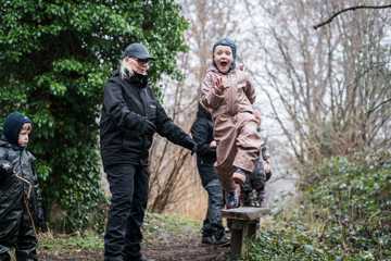 Et barn i Skårup Skovmølle springer fra en bænk, mens en voksen passer på.