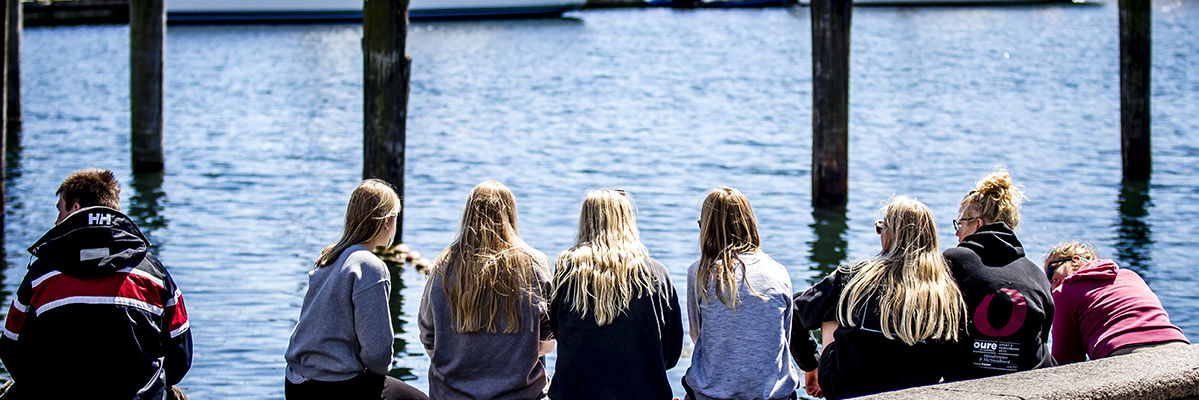 Unge sidder på kajkanten