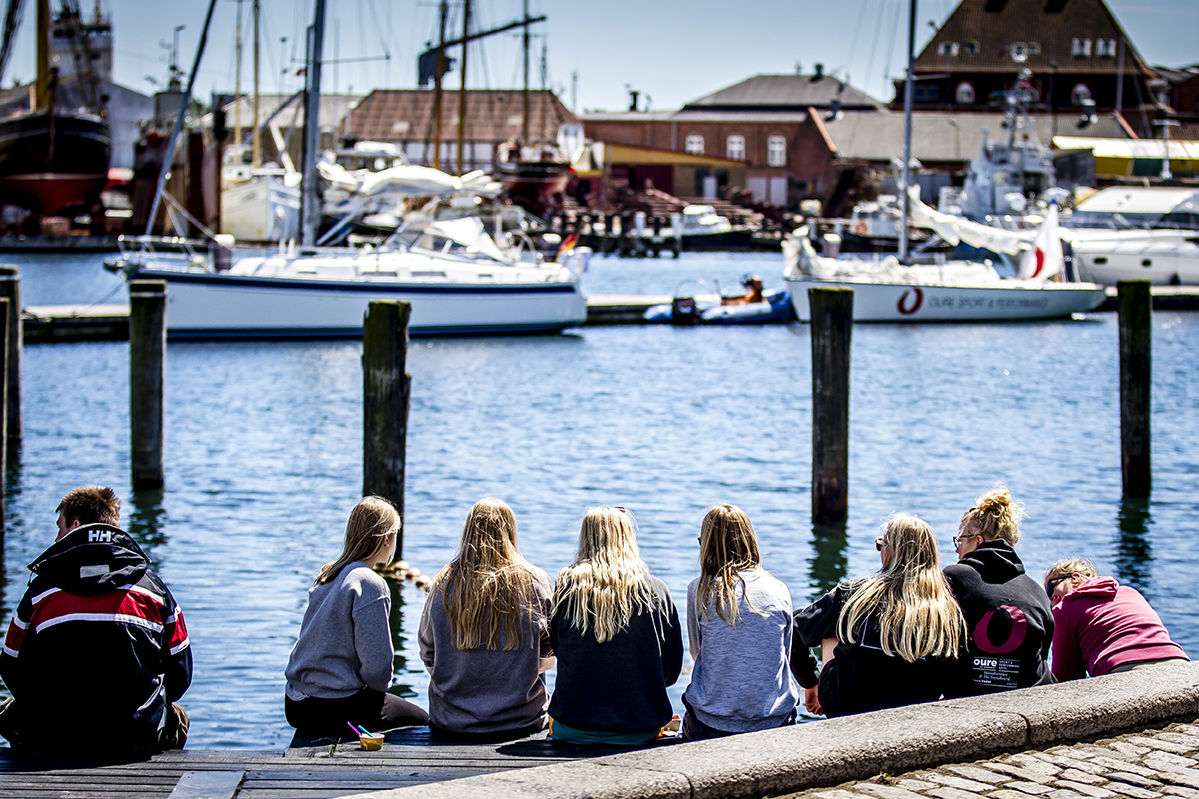 Unge sidder på kajkanten