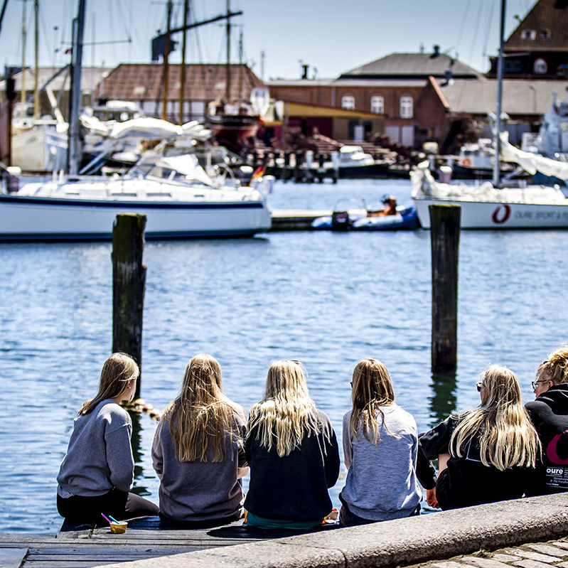 Unge sidder på kajkanten